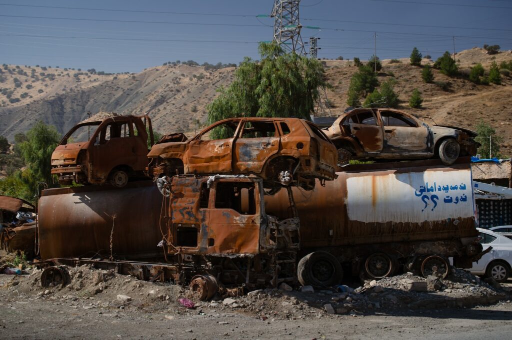 a rusted out truck sitting on top of a pile of junk